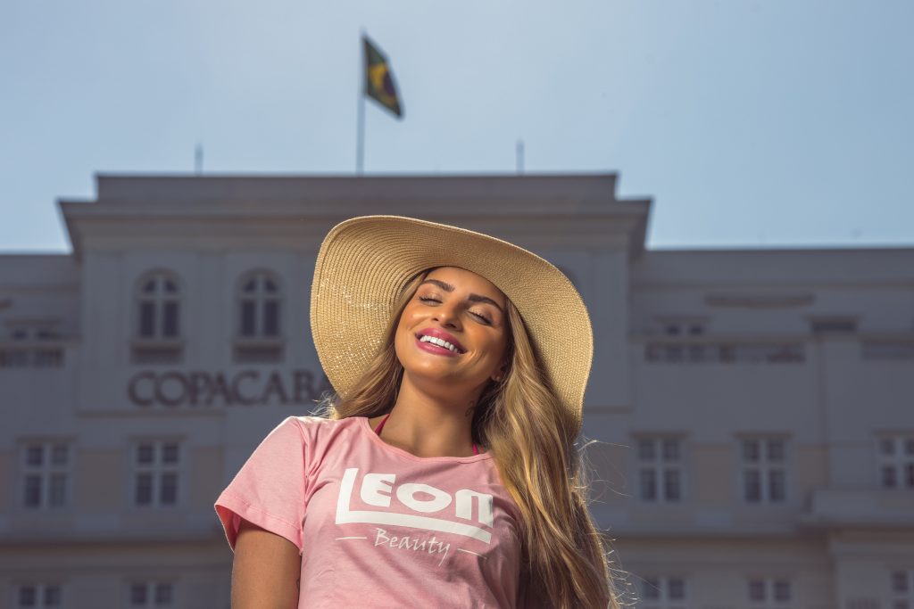 Woman in a sun hat and Leon Beauty T-shirt outside the Copacabana Palace